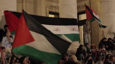 BRÜKSEL, BELGIUM - 27 Eylül 2025: Filistin ulusal bayraklı insanlar Place de la Bourse yavaş çekimde basamaklara otururlar. Orta Doğu 'daki savaşı protesto eden siyasi aktivistler