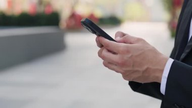 İş adamlarının yakın görüntüsü şehir merkezindeki akıllı telefondan mesaj yazıyor. Erkek girişimci metinleri cep telefonunda Megapolis Caddesi 'nin kapanışında duruyor. İletişim