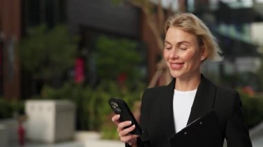 Kadın portresi akıllı telefon tebessümlerine bakar ve şehir merkezinde yürür. Panoya sahip kadın girişimci, yaz kasabası ağır çekim caddesinde cep telefonundan mesajlar alıyor