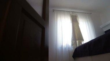 Güzel düğün elbisesi bir pencerede asılı. Genç gelin pencerenin yaklaşımlar