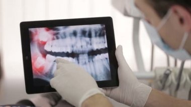 Diş hekimi bir hastanın röntgeni Tablet üzerinde gösterir.
