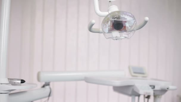 Zahnlicht-Ständer neben Zahnarztstuhl und Zahnarztutensilien. — Stockvideo