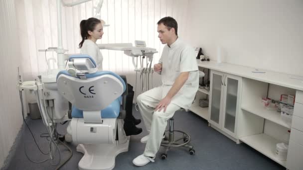 Joven dentista hablando con hermosa paciente femenina del consultorio dental — Vídeos de Stock