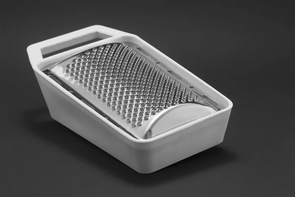 Grater with white plastic lining on a black background — Stock Photo, Image