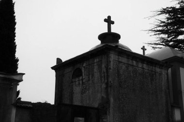 Gri gökyüzünün altında Hristiyan haçı olan eskimiş taş bir anıt mezar.