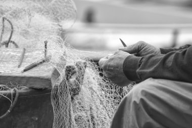 Hands of commercial fisherman mending nets clipart