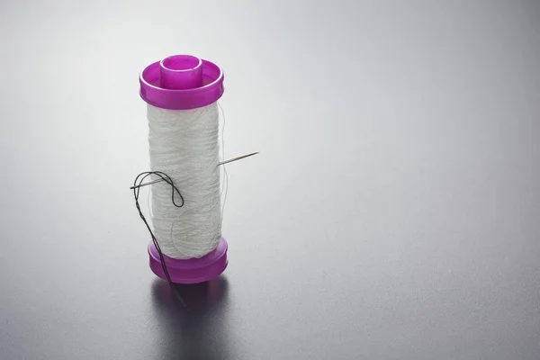 Hilo de bobina con aguja de coser blanca aislada en gris —  Fotos de Stock