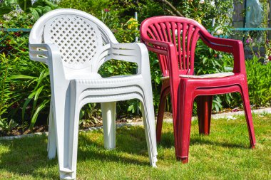 Yaz bahçesinde yeşil çimlerin üzerinde beyaz plastik sandalye