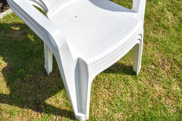 夏の庭の緑の芝生の上の白いプラスチック椅子 — ストック写真