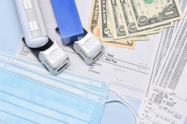 Coronavirus salgınına karşı taşımacılık departmanı konseptinde bir kamyon oyuncağı, dolar ve yüz maskeli maaş bordrosu..