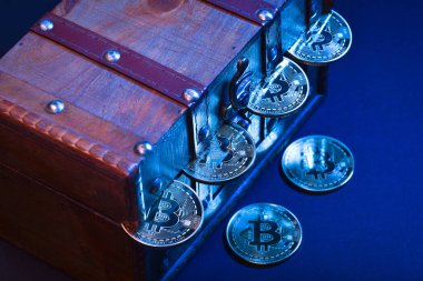 Değerli eşyalarla dolu ahşap hazine sandığı, bitcoinler, bozuk paralar veya karanlık arka planda izole edilmiş dolar.