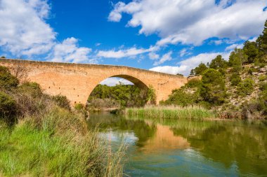 Antique one arch stone bridge over a river the Hoces del Rio Cabriel Natural Park between Valencia and Cuenca in Spain. Protected Area.  clipart