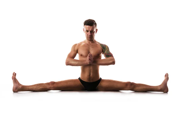 Joven hombre fuerte haciendo yoga y gimnasia, cross-twine . —  Fotos de Stock