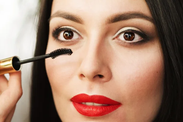 Beautiful young brunette woman doing makeup. — Stock Photo, Image