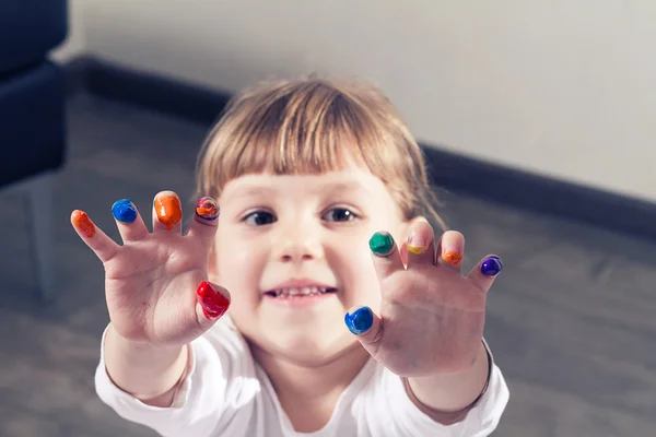 Красивая маленькая девочка рисует пальцами — стоковое фото