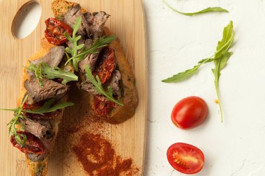 İtalyan usulü çavdar ekmeğinden bruschetta, füme et ve bruschetta üzerinde güneşte kurutulmuş domates.