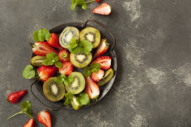 Koyu arkaplanda parlak ve taze çilek ve kivi.