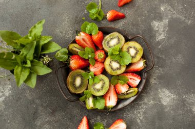 Koyu arkaplanda parlak ve taze çilek ve kivi.