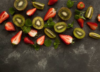 Koyu arkaplanda parlak ve taze çilek ve kivi.