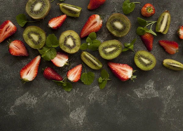 Koyu arkaplanda parlak ve taze çilek ve kivi.