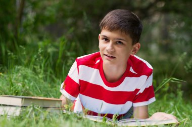 boy reading a book on grass