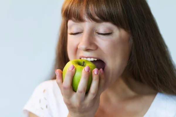 girl biting green apple