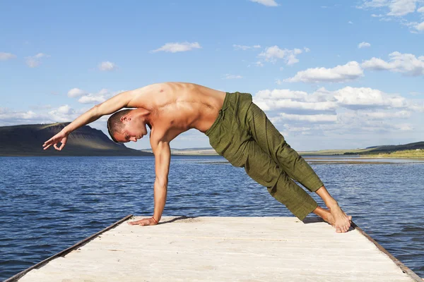 Man practices yoga and gymnastics near the lake — Stock Photo, Image