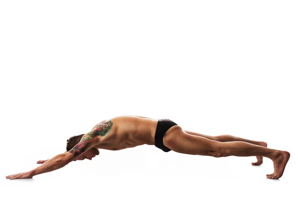 Joven hombre fuerte haciendo yoga y gimnasia, entrenamiento de fuerza —  Fotos de Stock