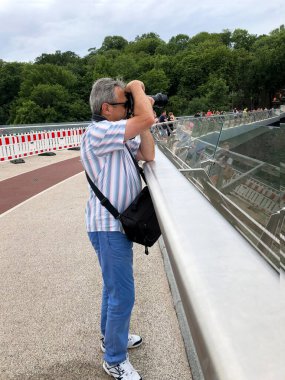Bir adam bir yaz günü bir köprüde fotoğraf çekimi yapar.