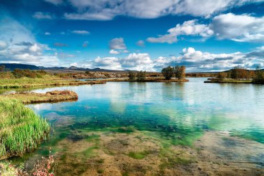 Turkuaz turkuaz renkli, parlak, bulutlu bir günde cam gibi berrak bir gölet.