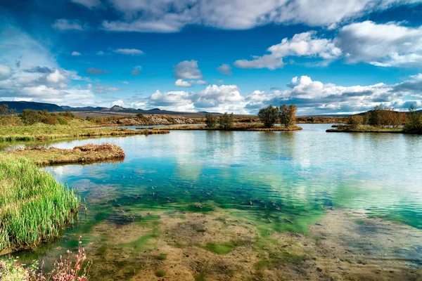 Turkuaz turkuaz renkli, parlak, bulutlu bir günde cam gibi berrak bir gölet.