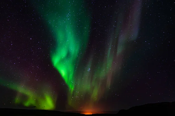 Renkli kuzey ışıkları batan güneşin ışıltısının üzerinde dans eder