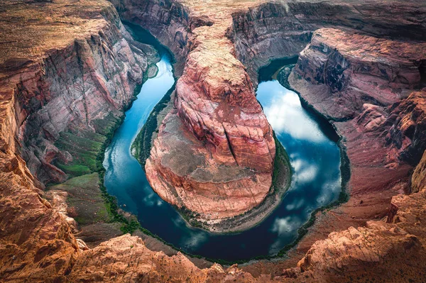 Arizona 'nın at nalı kıvrımı güneş batmadan hemen önce bir drondan alındı. Güzel mavi Colorado nehir suyu yukarıdaki tüylü beyaz bulutları yansıtıyor. Horseshoe Bend, Arizona 'nın Glen Kanyonu' nda bulunan ünlü bir anıttır.