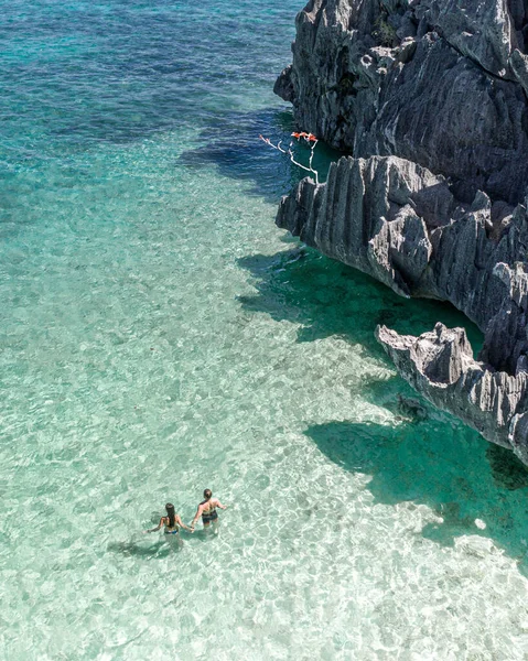 Pasifik Okyanusu 'ndaki bir adanın sığ sularında duran bir çift. Bu resim Filipinler 'deki Smith Beafh' da çekildi. Smith Sahili, Filipinler 'deki Coron Adası' nın hemen güneyindedir.