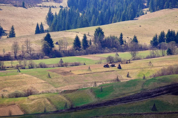 Slunečné jarní v horské vesnici. Pole a kopce — Stock fotografie