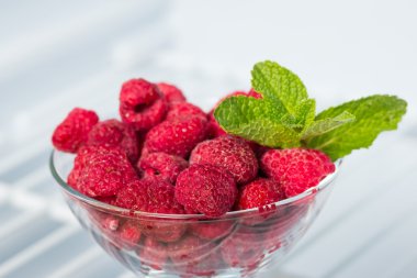 frozen raspberries in a glass piala and a sprig of mint clipart