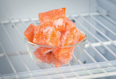 Sliced frozen pumpkin in the freezer in a glass piala