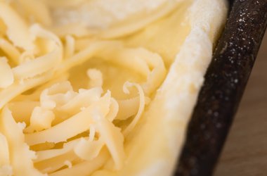 Grated cheese on a piece of dough on a baking sheet, close-up