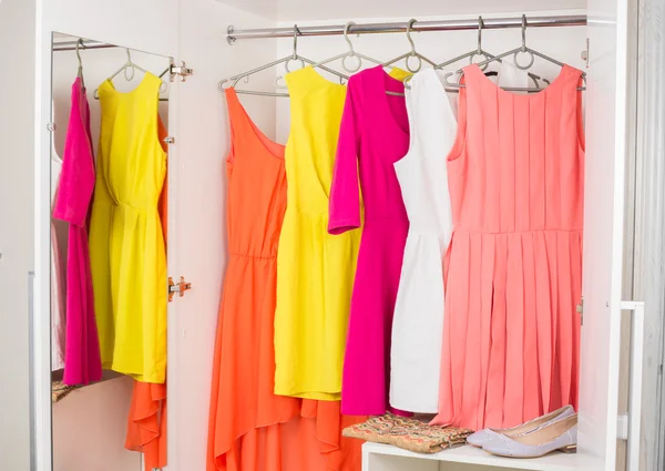 Row of bright colorful dress hanging on coat hanger, shoes and h — Stock Photo, Image
