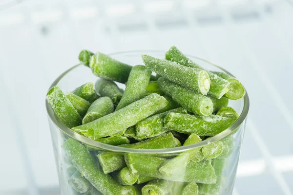 Frijoles verdes congelados en un vaso en el congelador — Foto de Stock
