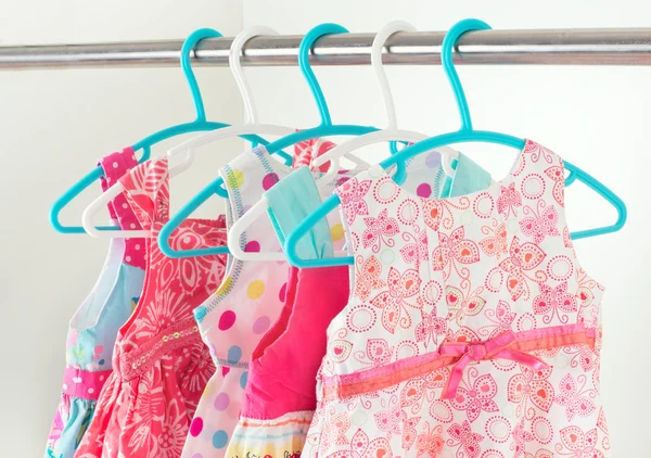 Row of little girl dresses hanging on coat hanger in white wardr — Stock Photo, Image