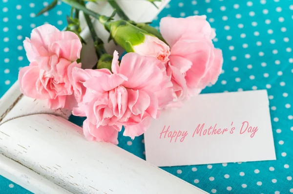 Greeting card with pink carnations on a bright blue background w