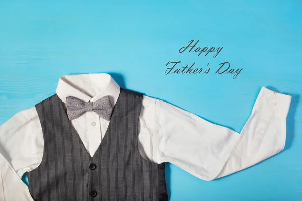 white shirt, gray vest and a bow tie on a bright blue background