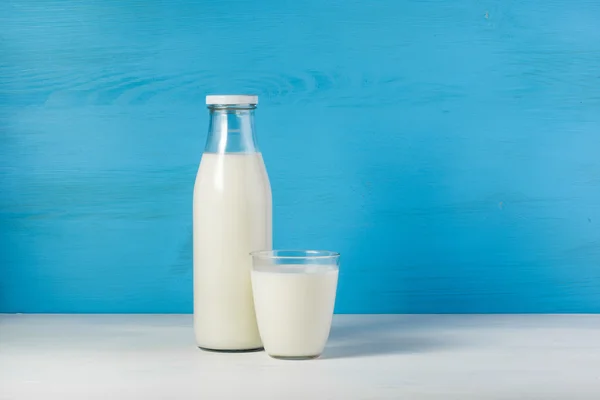 Бутылка деревенского молока и стакан молока на белом столе на — стоковое фото