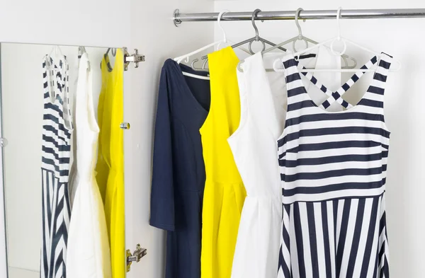 Modern fashion womens dresses on hangers in a white cupboard — Stok fotoğraf