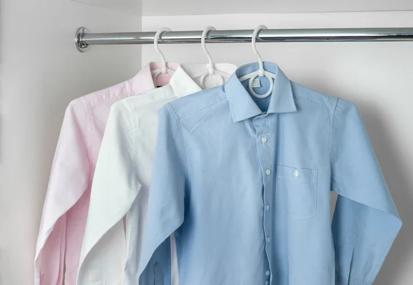 Camisas planchadas limpias blancas, azules y rosas para hombre que cuelgan de la percha —  Fotos de Stock
