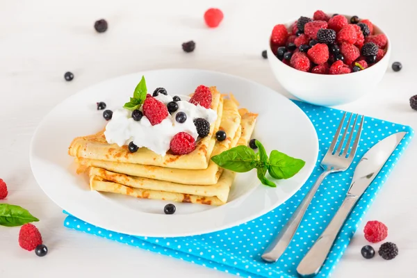 Delicious sweet crepes decorated air cream and ripe berries