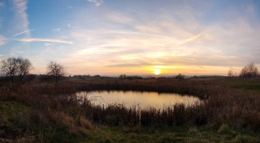 Gün batımı bulutlu gölet manzarası