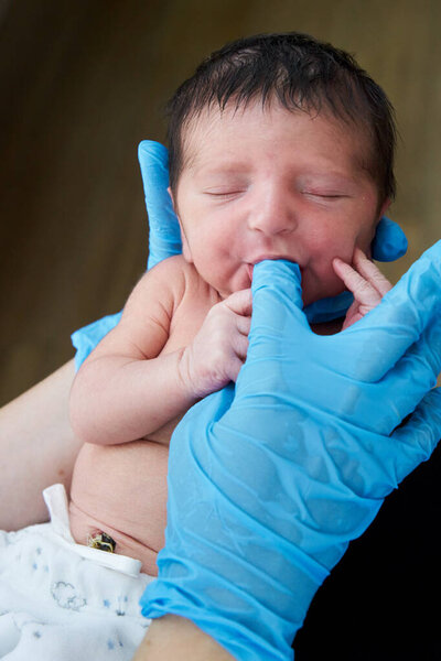 Young female doctor helping newborn baby and testing