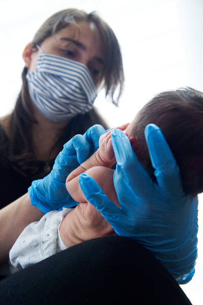Young female doctor helping newborn baby and testing
